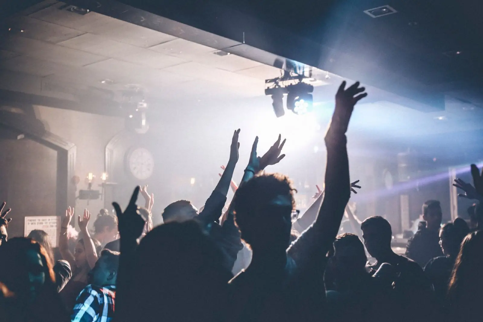 People dancing beneath blue and white lights at a nightclub